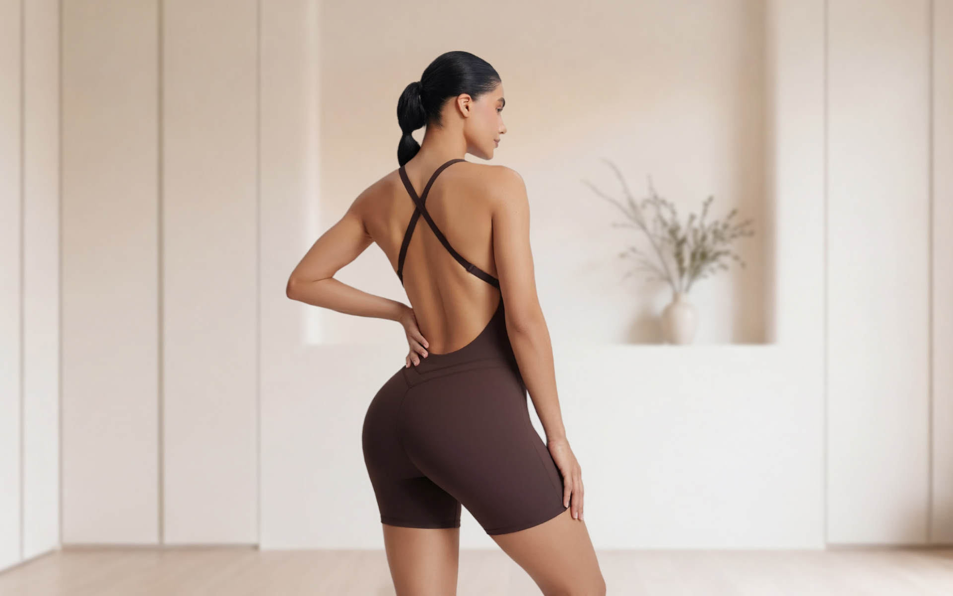 Woman in workout attire posing in a fitness studio, illustrating a Brazilian butt squat challenge focused on lower-body strength and glute exercises.