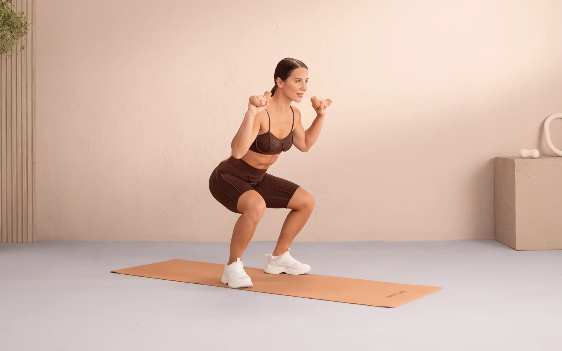 Woman performing a weighted squat on a mat for a 30-day abs squat challenge.