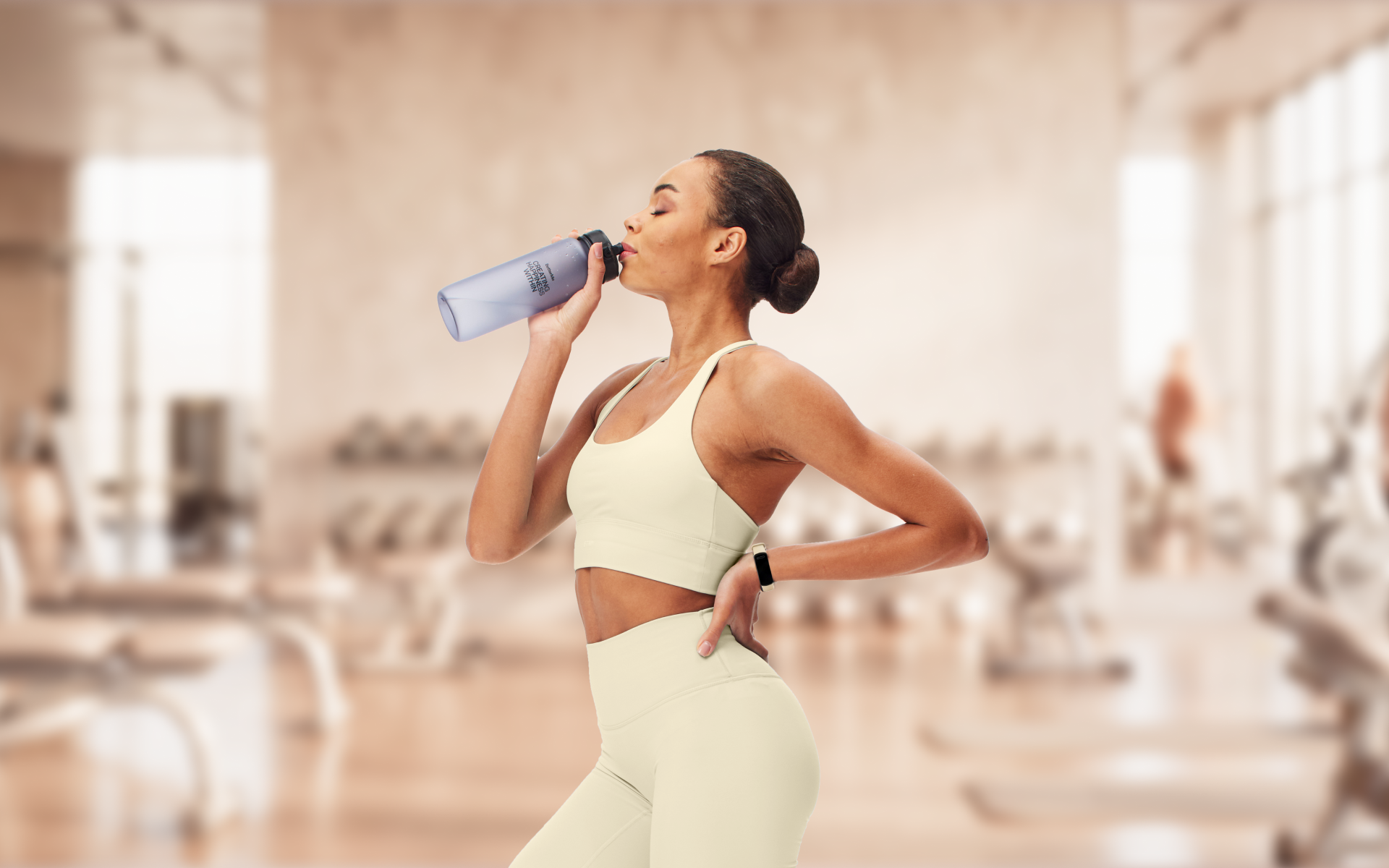 Woman drinking water at the gym after a full-body workout 3 times a week.