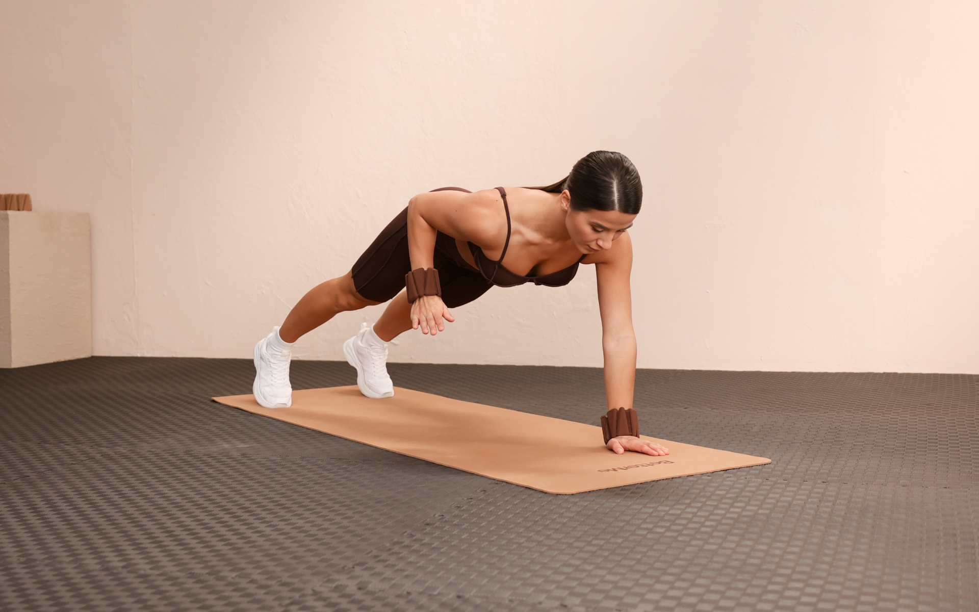 Woman doing a plank exercise with wrist weights for planking for weight loss.