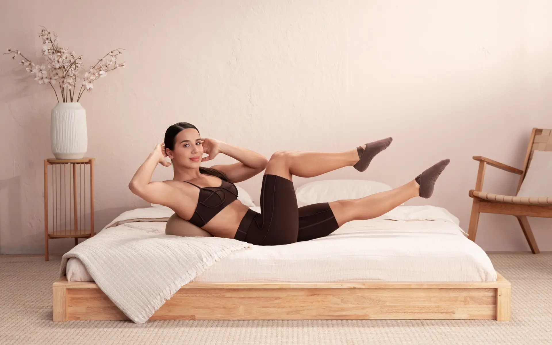 Woman performing bicycle crunches on a bed to demonstrate different types of crunches.