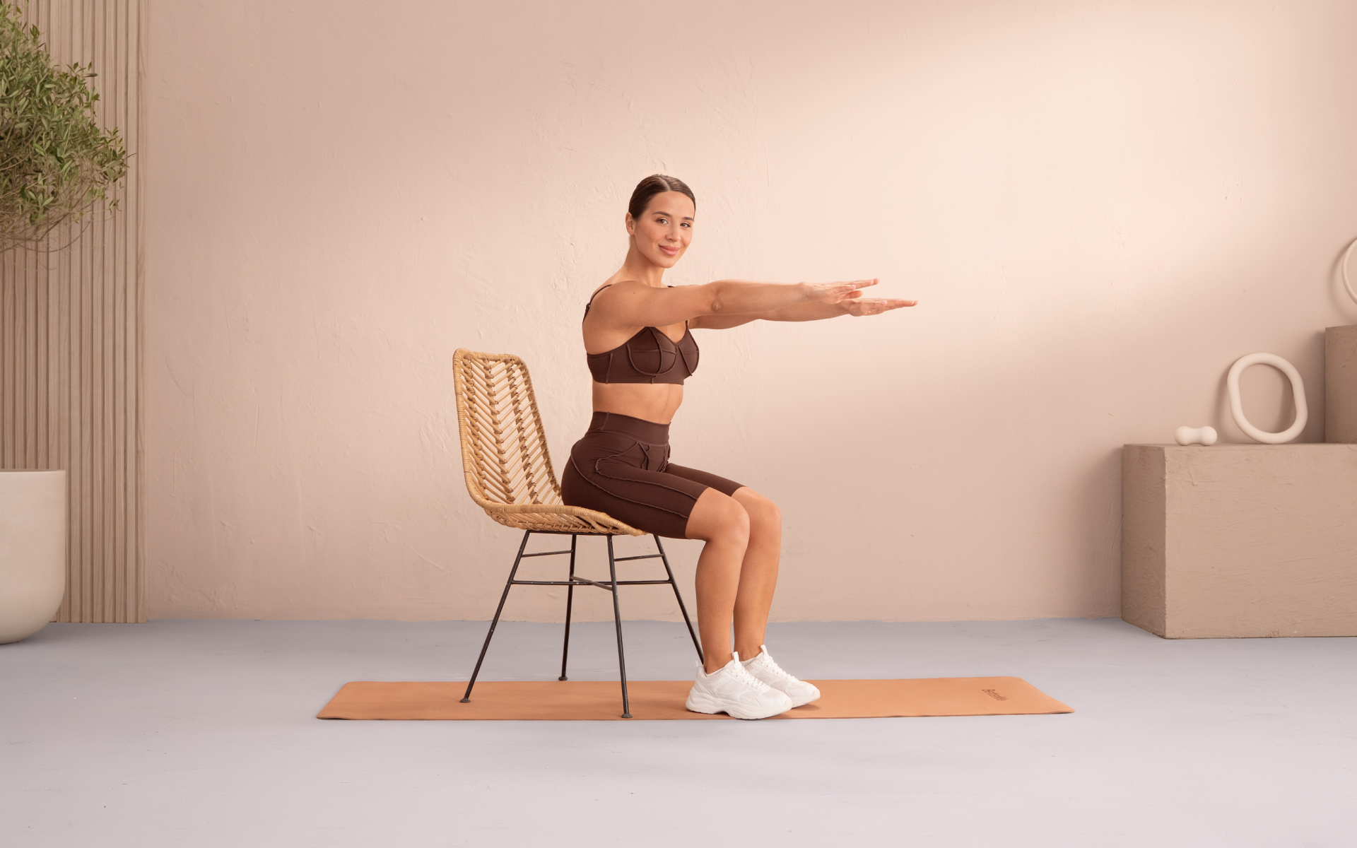 Woman performing a seated chair exercise at home for a 2-week workout challenge.