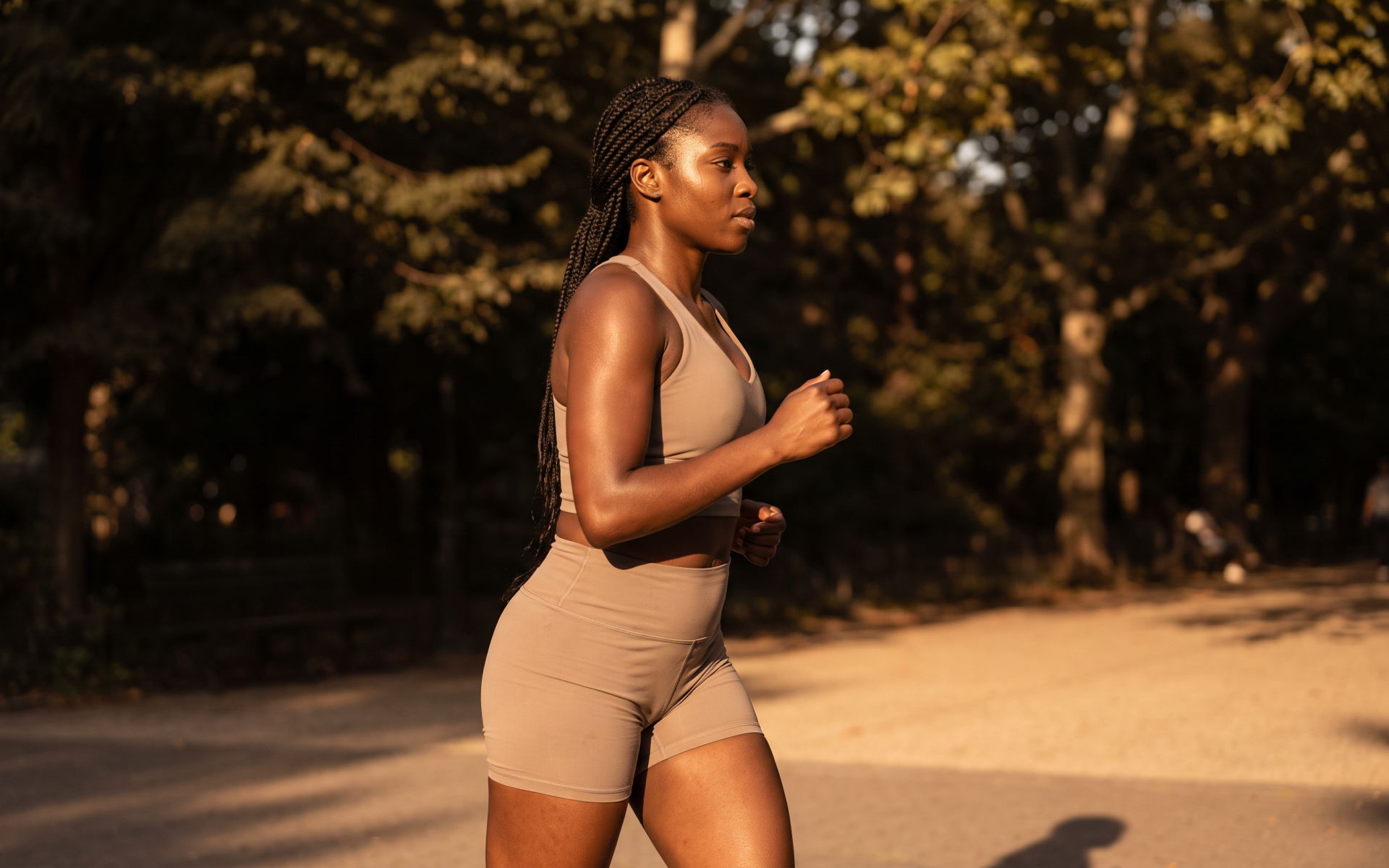 Woman running 4 miles outdoors on a park path during a fitness workout.