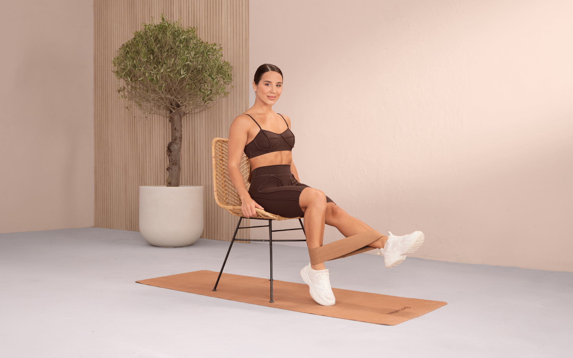 Woman doing seated ankle resistance band exercises using a chair.