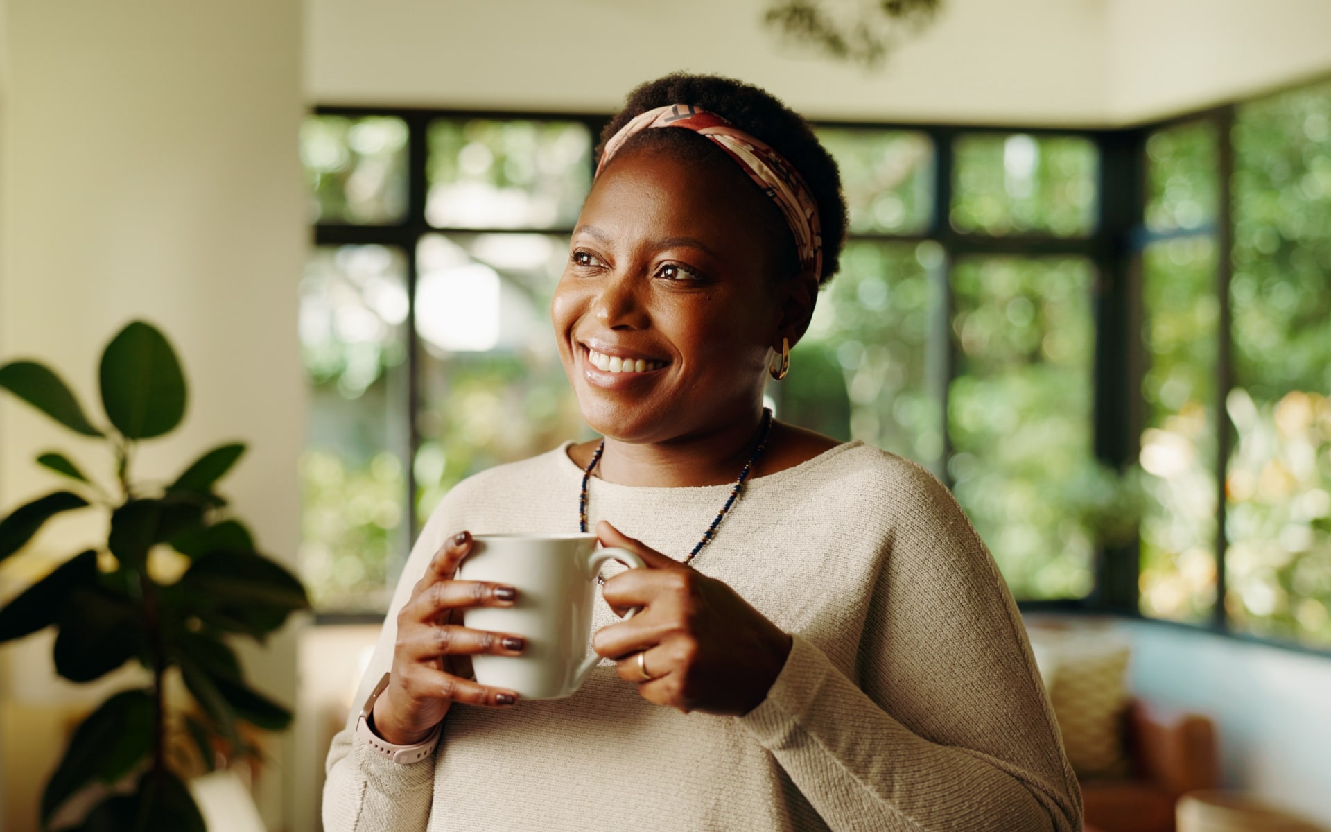Smiling woman holding a mug in a sunlit home, illustrating intermittent fasting coffee and a simple morning drink during fasting hours.