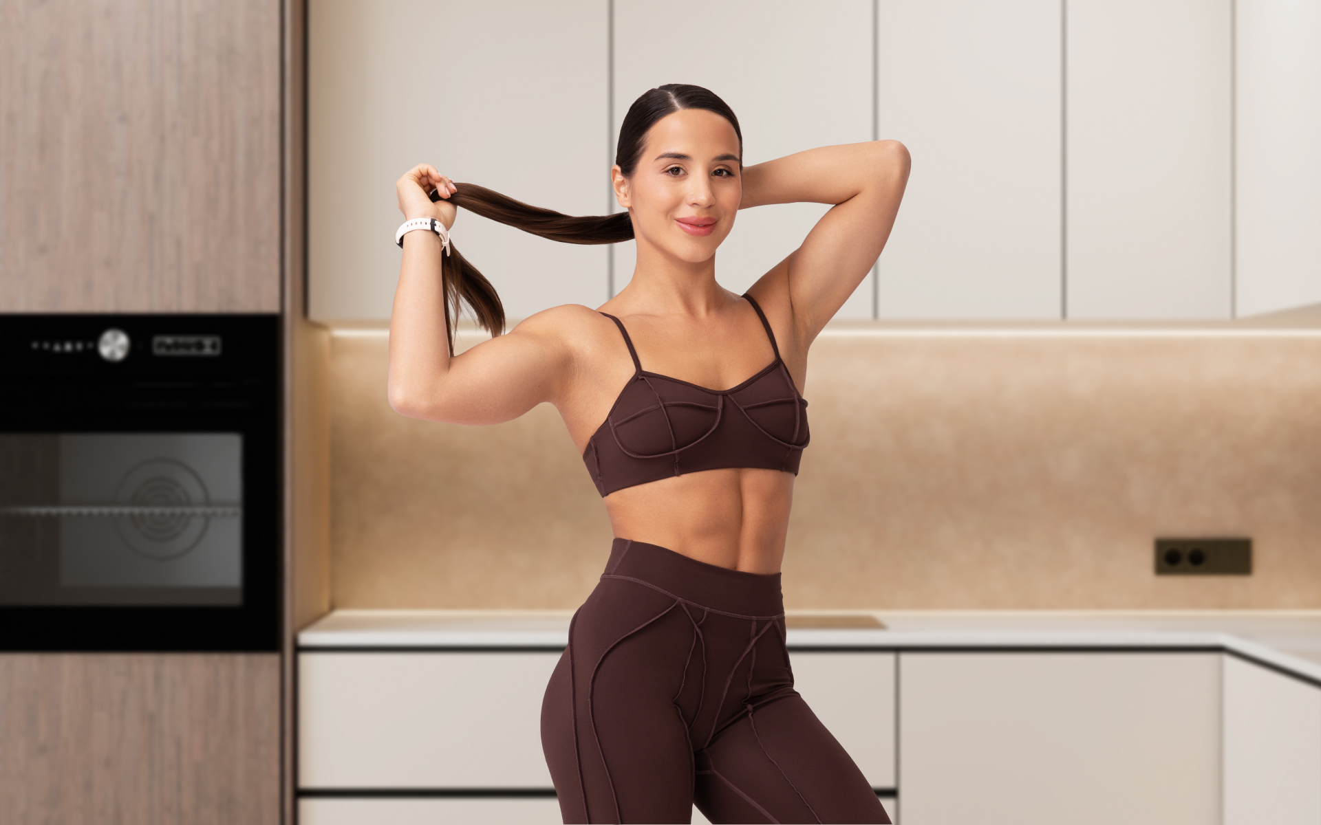 Fit woman posing in a kitchen, illustrating intermittent fasting belly fat and body composition goals within a healthy lifestyle.