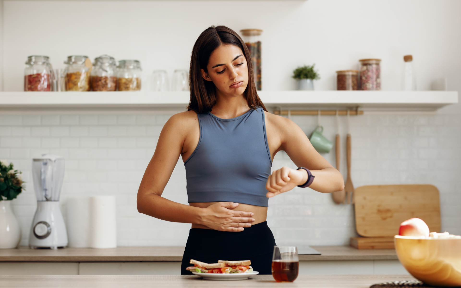 Woman checking the time in her kitchen before eating, illustrating the question, “Can intermittent fasting cause weight gain?”