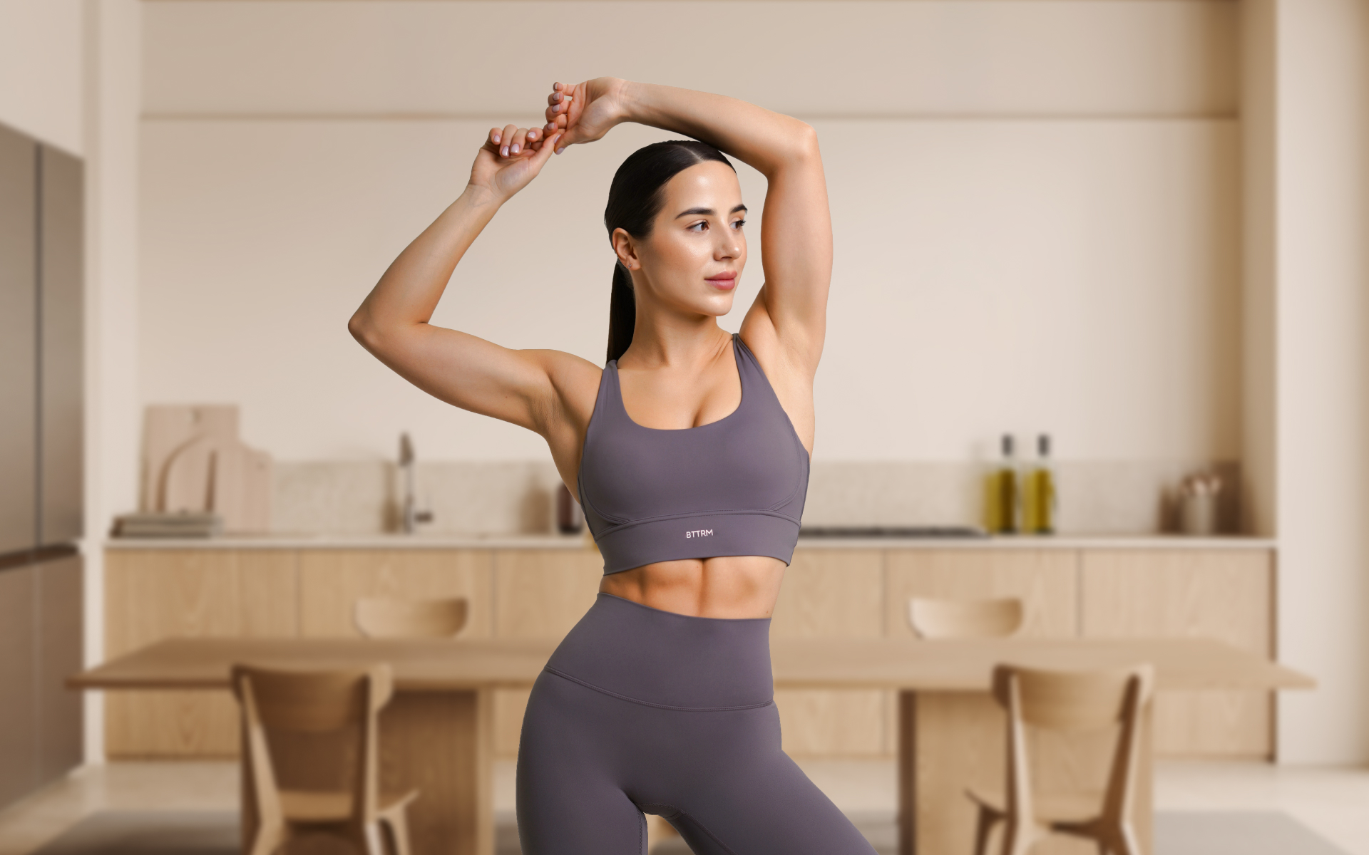 Woman stretching with her arms overhead in a kitchen while learning how much weight can you lose in a 24-hour fast.