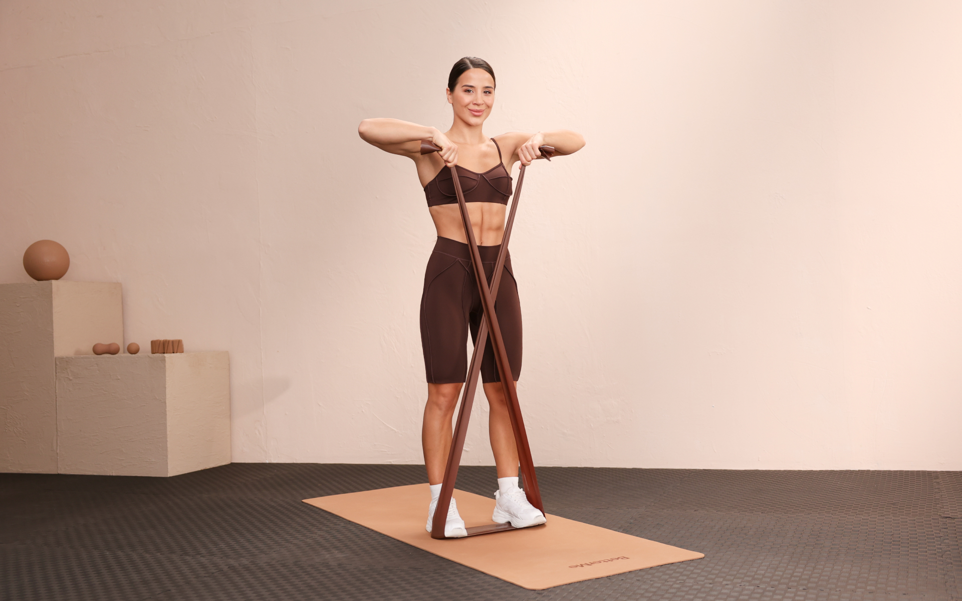 Woman performing a standing resistance-band exercise during a BetterMe Pilates workout.