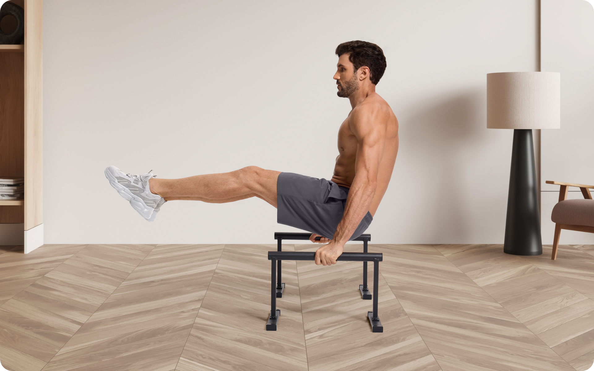Man performing an L-sit on parallettes in a minimal indoor setting