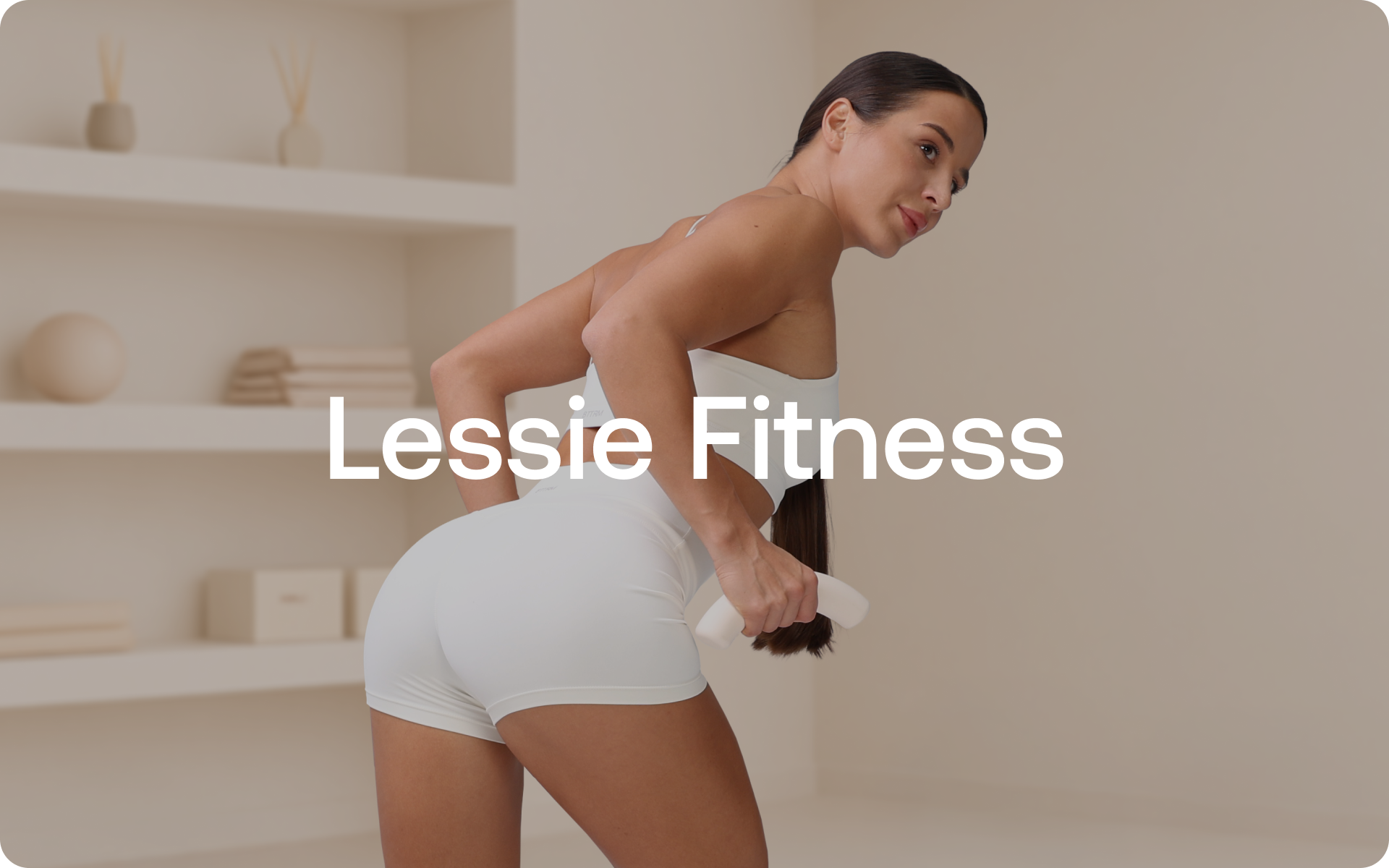 Lessie Fitness showing a close-up of a model in a white workout set performing a bent-over row with hand weights in a neutral studio.