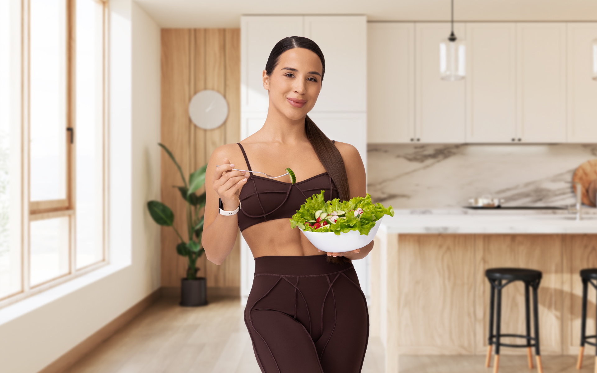 Woman holding a bowl of fresh salad in a bright kitchen, illustrating an intermittent fasting diet plan focused on balanced, healthy meals.