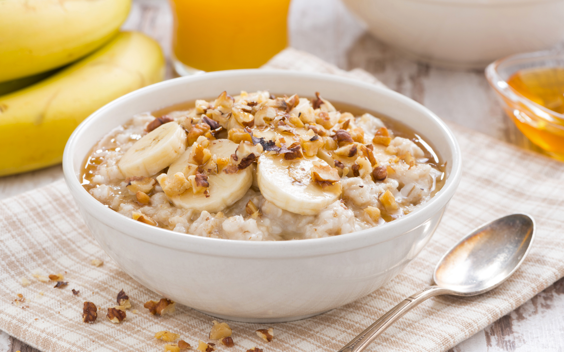 Bowl of oatmeal topped with banana slices, chopped nuts, and a drizzle of syrup, illustrating a high protein plant based meal plan with a simple, nourishing breakfast.