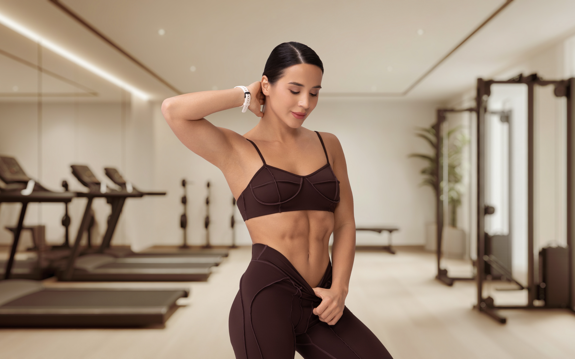 Fit woman posing in a modern fitness studio, illustrating a back to gym routine and renewed motivation for strength training.
