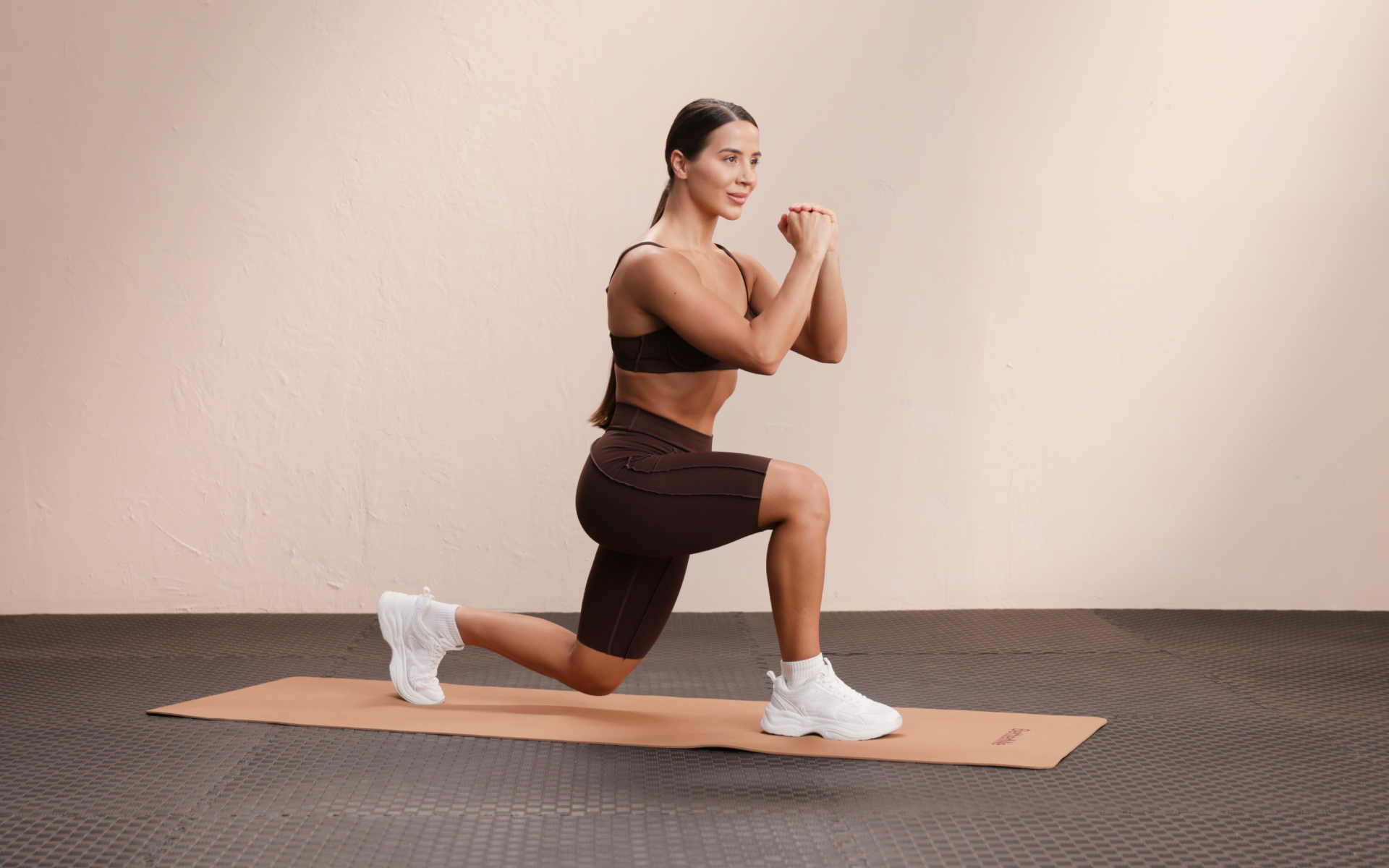 Woman performing a lunge on a yoga mat as part of a 30 minute calisthenics workout.