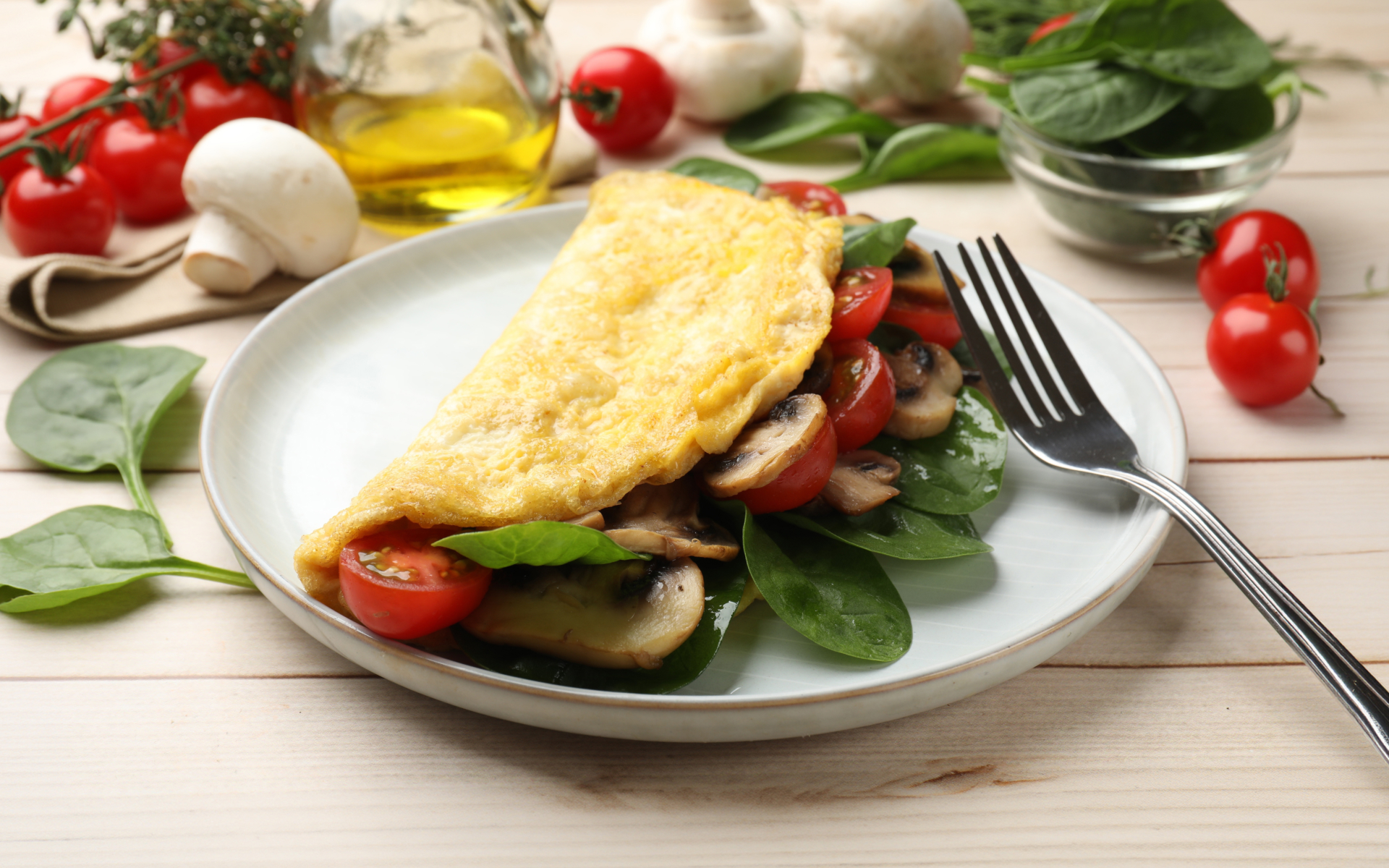 Omelet with spinach, mushrooms, and tomatoes on a plate as part of a high fiber low carb diet plan.