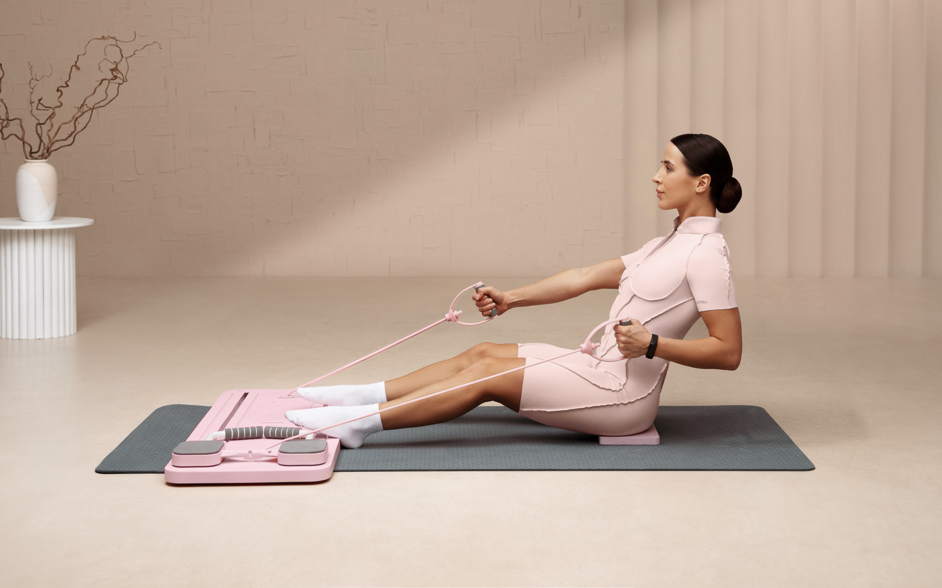 Woman uses a Pilates reformer-style resistance machine on a mat during a beginner Pilates workout.