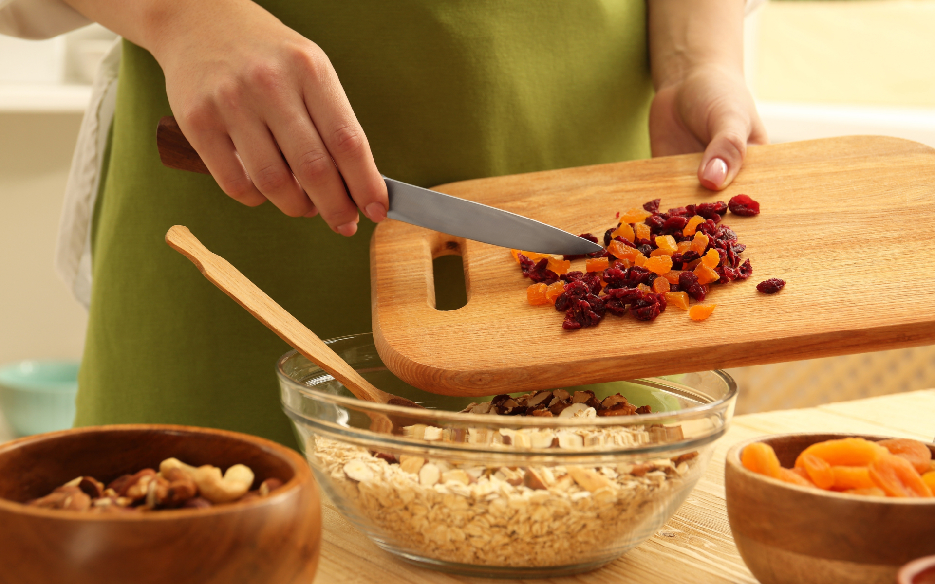 Person chopping dried fruit and nuts into a bowl of oats for intermittent fasting and fiber meal planning.