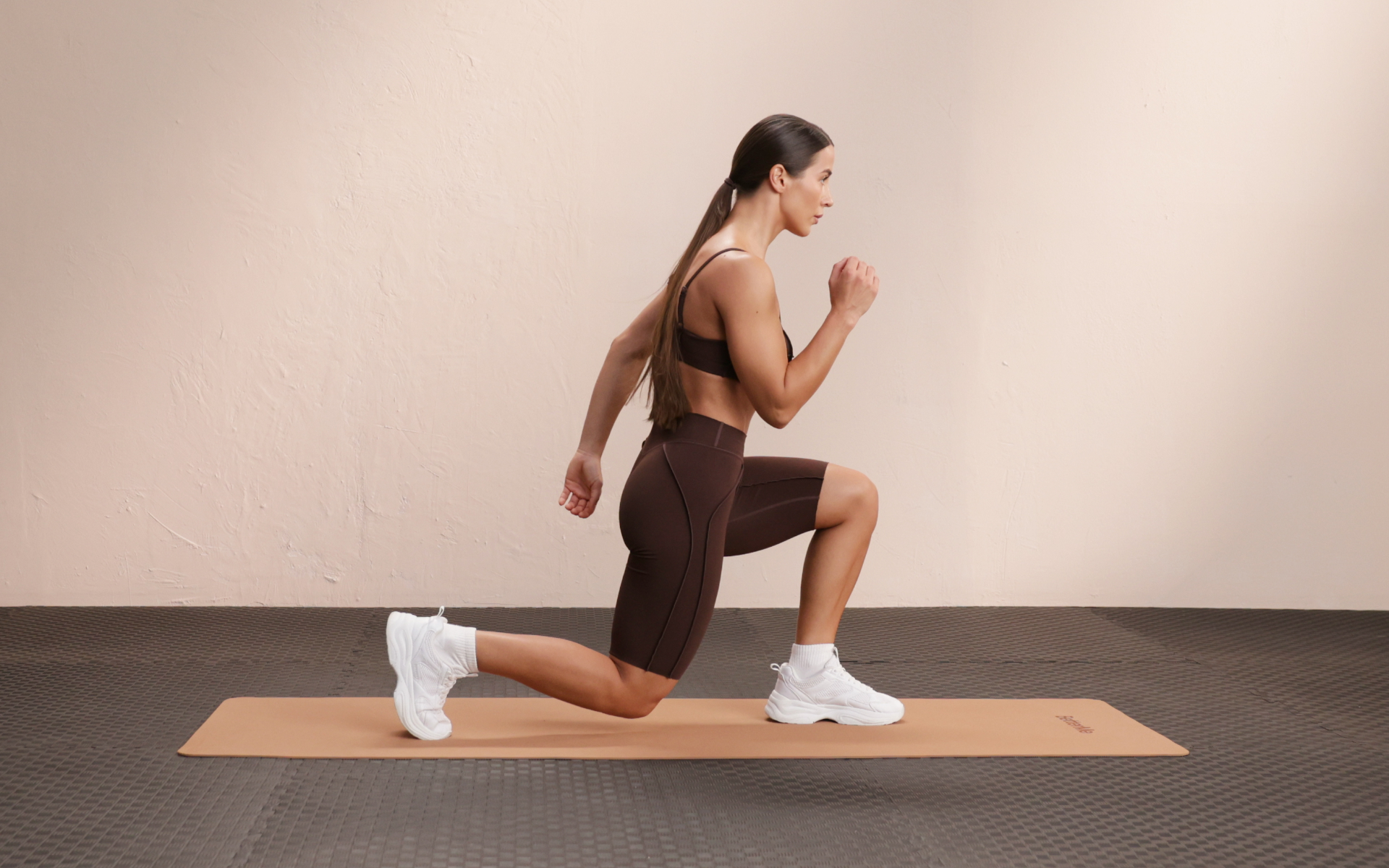 Woman performing a reverse lunge during a low impact leg workout on an exercise mat.