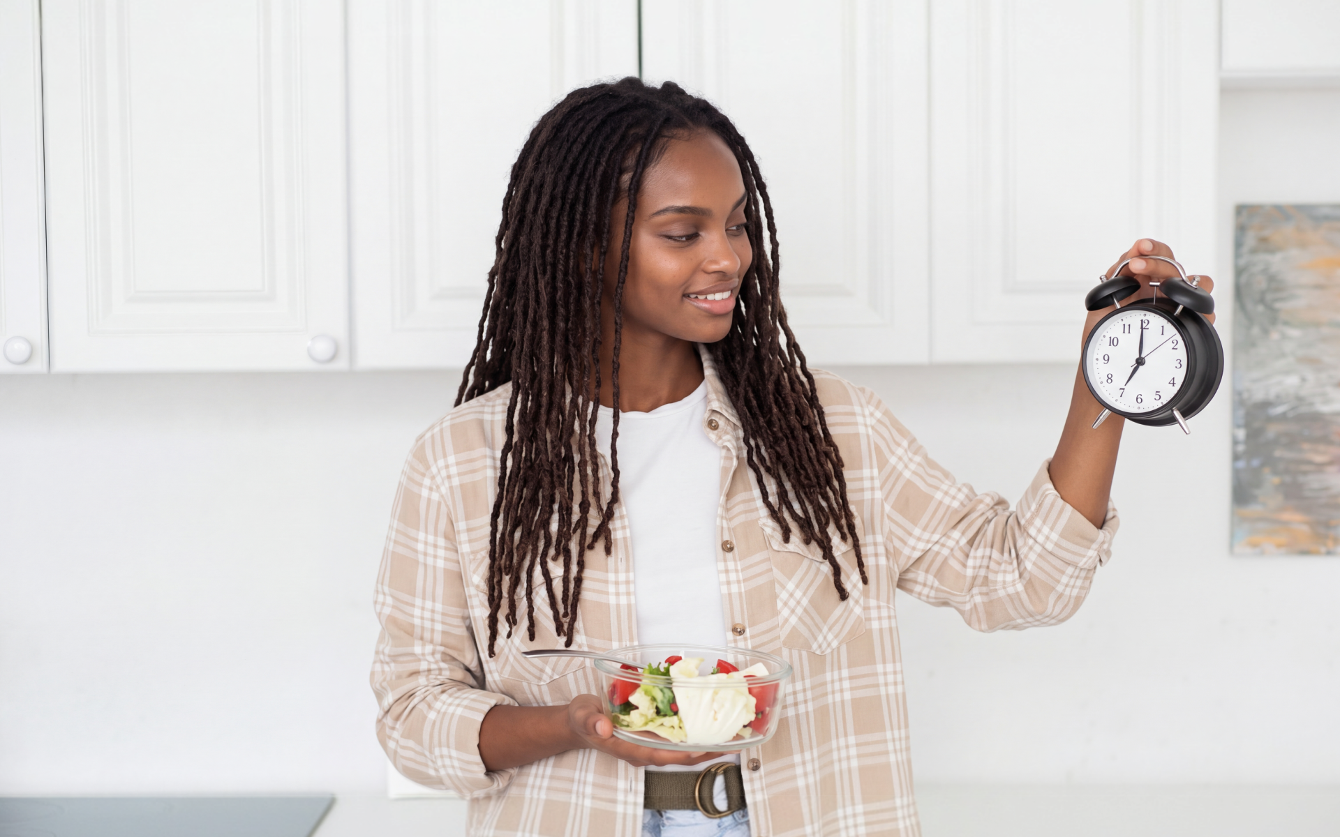 Woman holding a bowl of food and an alarm clock to compare a 24 vs 48 hour fast.