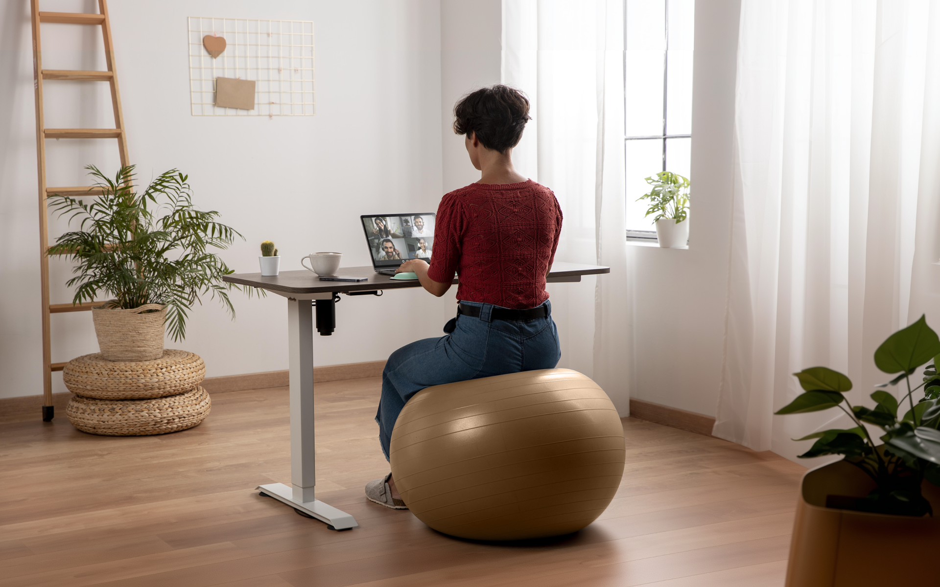 Person sitting on a yoga ball at a standing desk while working from home, illustrating the benefits of a yoga ball chair.
